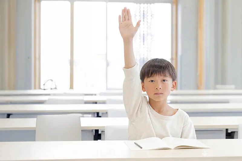 キュリオキッズの教室で手を挙げる小学生の男の子