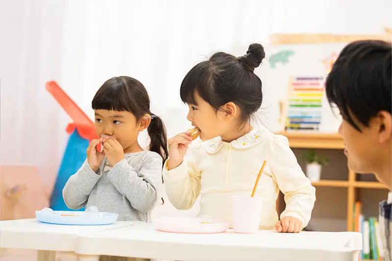 キュリオキッズの教室で給食を食べる笑顔の子供たち