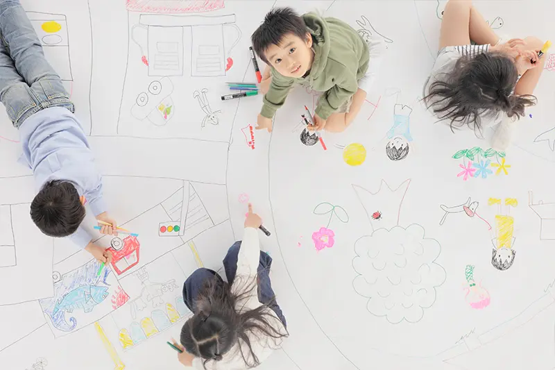 キュリオキッズの子どもたちが床で絵を描く
