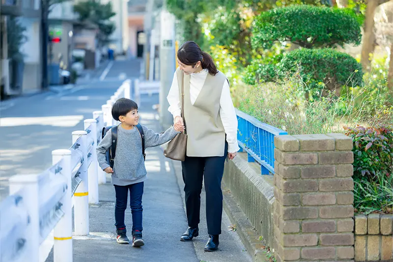 母親と子供が手を繋いで歩道を歩いている