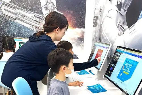 キュリオキッズの日本人講師と子供がコンピューターを使って学習している様子