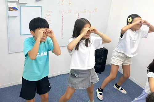 キュリオキッズの教室で体操をする3人の子供たち