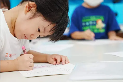 キュリオキッズの子供が鉛筆で紙に書いている様子