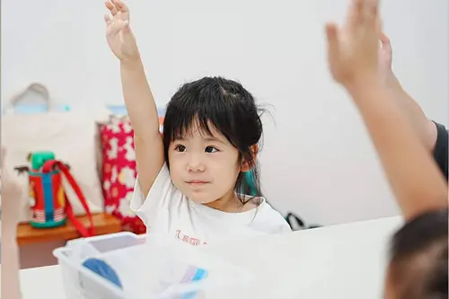 キュリオキッズの教室で手を挙げる女の子